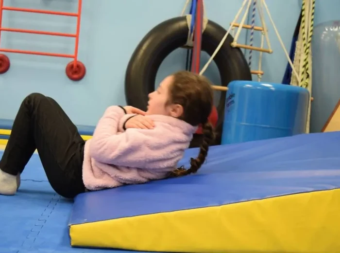 Girl doing a sit-up on a foam wedge in the therapy gym