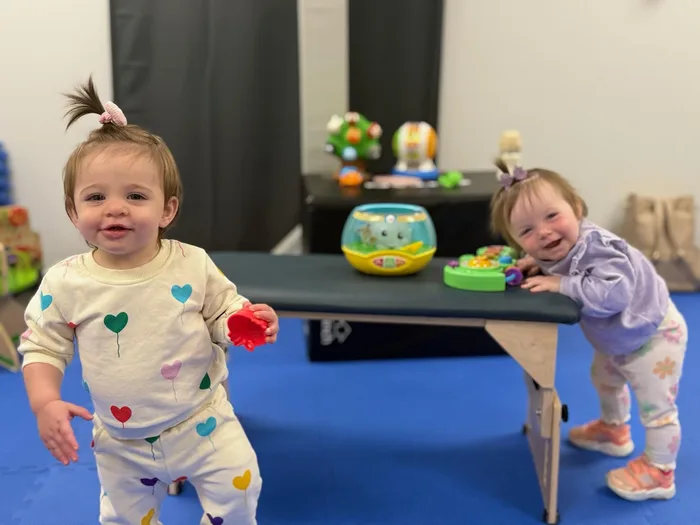 Two toddlers playing standing at a low table in the therapy gym
