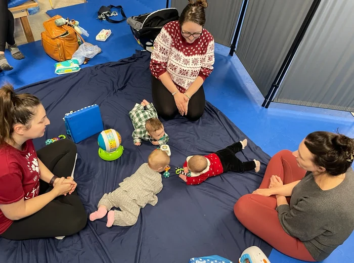 Babies on mats during a tummy time class with parents kneeling alongside