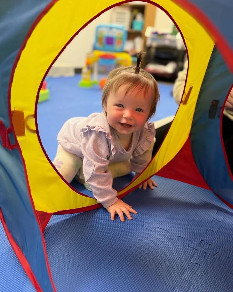 Pediatric therapist and parent watching a child practice a new skill together
