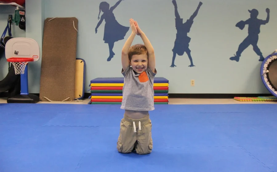 Pediatric physical therapist guiding a toddler through a balance activity in the Port Chester gym